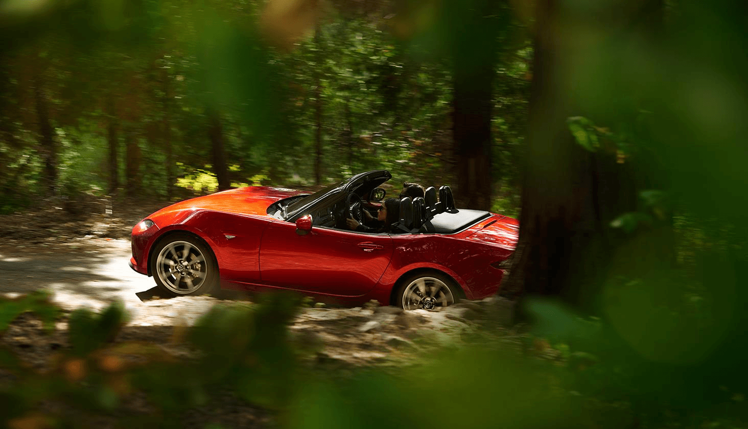 Mazda MX-5 2020 rouge, à ciel ouvert, roulant en forêt